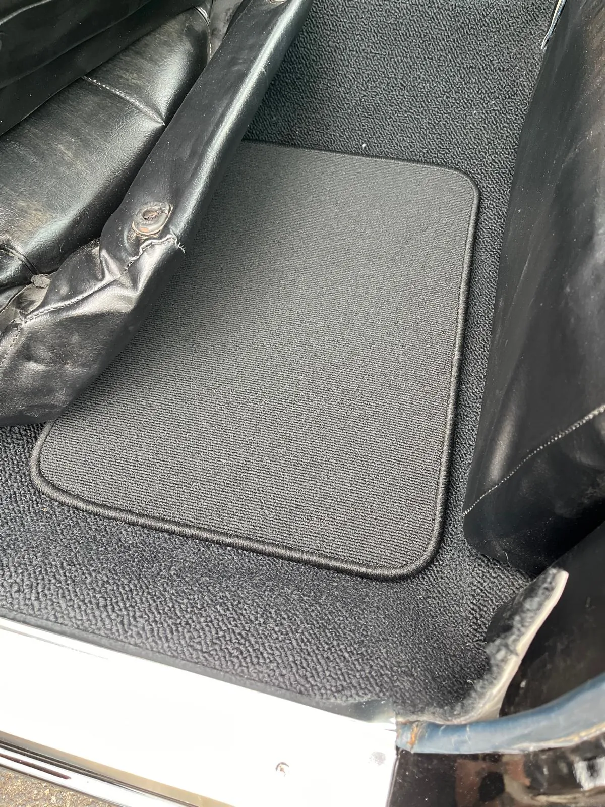 Blick hinter den Fahrersitz eines Buick Riviera 1964. Dort liegt eine graue Fußmatte.