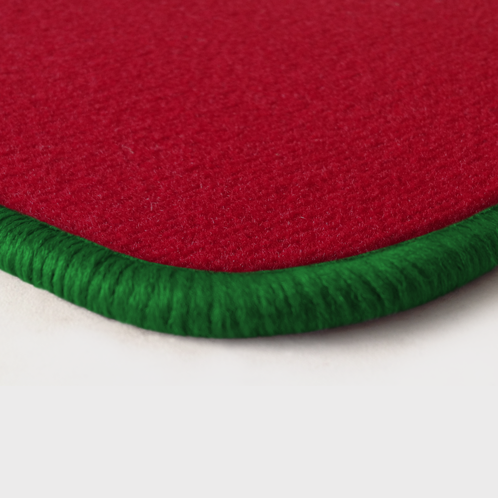 Eine Ecke als Beispiel einer Fussmatte Velours rot mit Rand in gruen.