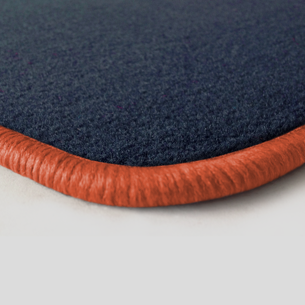 Eine Ecke als Beispiel einer Fussmatte Velours dunkelblau mit Rand in lachs.