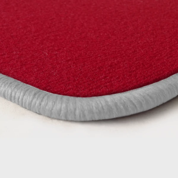 Eine Ecke als Beispiel einer Fussmatte Velours rot mit Rand in weiss.