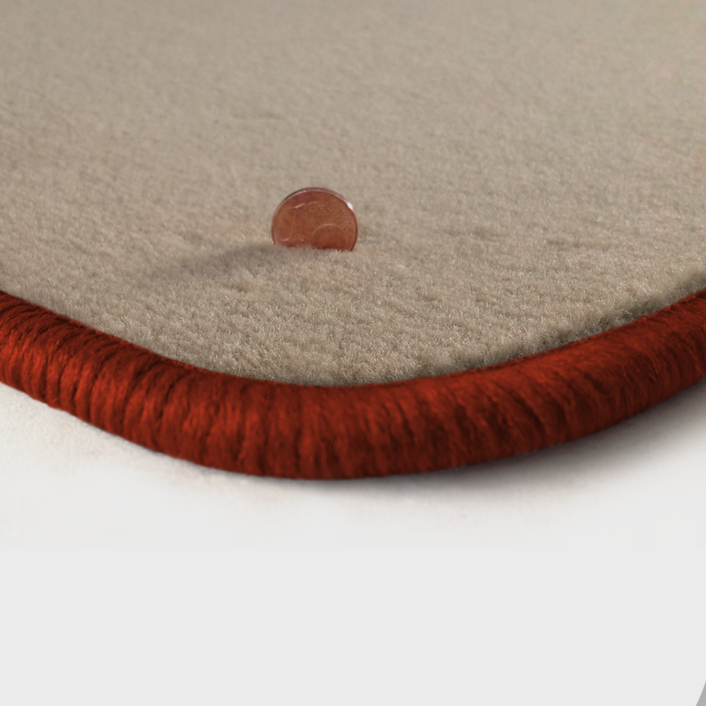 Eine Ecke als Beispiel einer Fussmatte Velours beige mit Rand in kupfer.