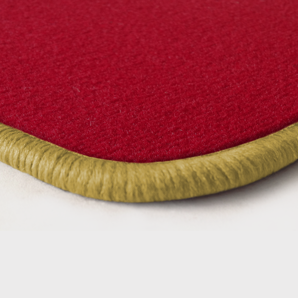 Eine Ecke als Beispiel einer Fussmatte Velours rot mit Rand in safran.
