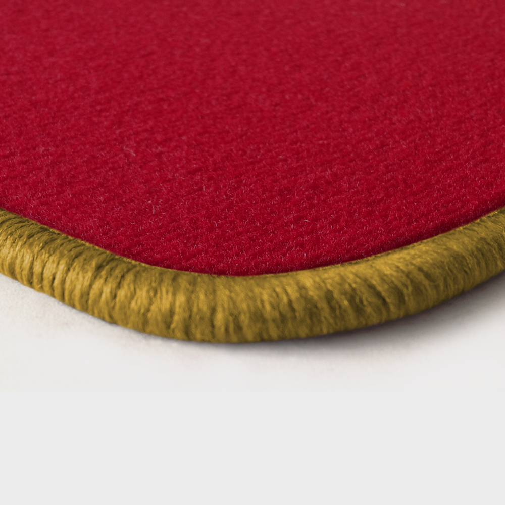 Eine Ecke als Beispiel einer Fussmatte Velours rot mit Rand in gold.