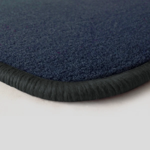 Eine Ecke als Beispiel einer Fussmatte Velours dunkelblau mit Rand in dunkelgrau.