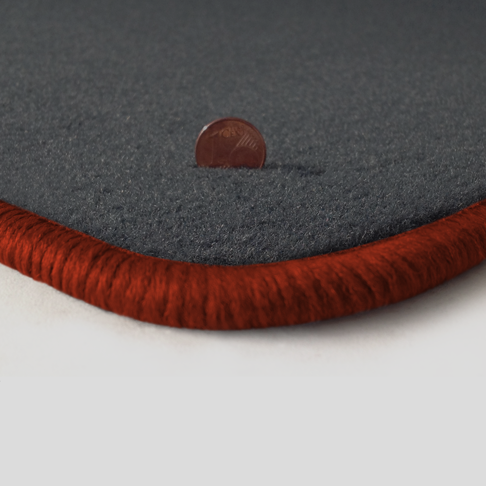 Eine Ecke als Beispiel einer Fussmatte Velours dunkelgrau mit Rand in kupfer.