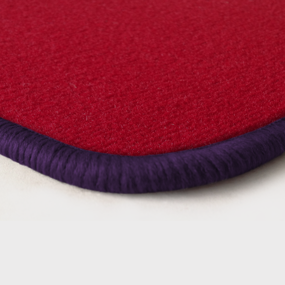 Eine Ecke als Beispiel einer Fussmatte Velours rot mit Rand in violett.