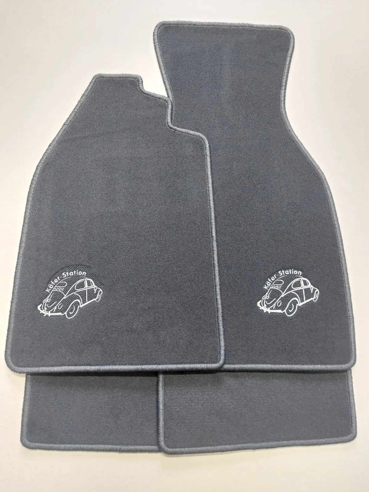 Vier Fußmatten mit der Aufdruck eines VW Käfers und „Käfer Station“ Schriftzug
