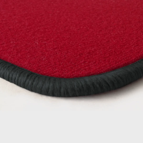 Eine Ecke als Beispiel einer Fussmatte Velours rot mit Rand in dunkelgrau.