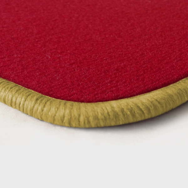 Eine Ecke als Beispiel einer Fussmatte Velours rot mit Rand in safran.