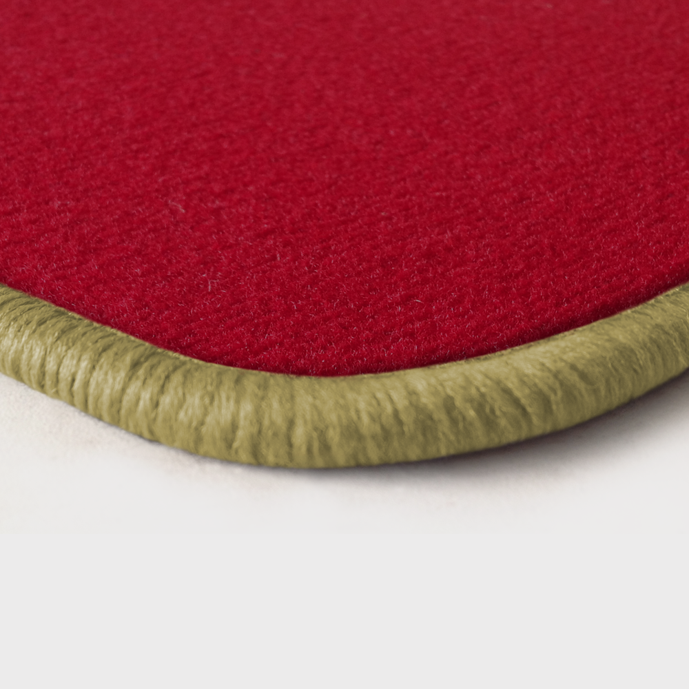 Eine Ecke als Beispiel einer Fussmatte Velours rot mit Rand in mittelbeige.